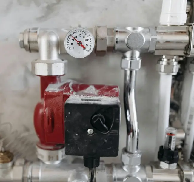 red valve along with silver pipe and pressure meter with black control valve
